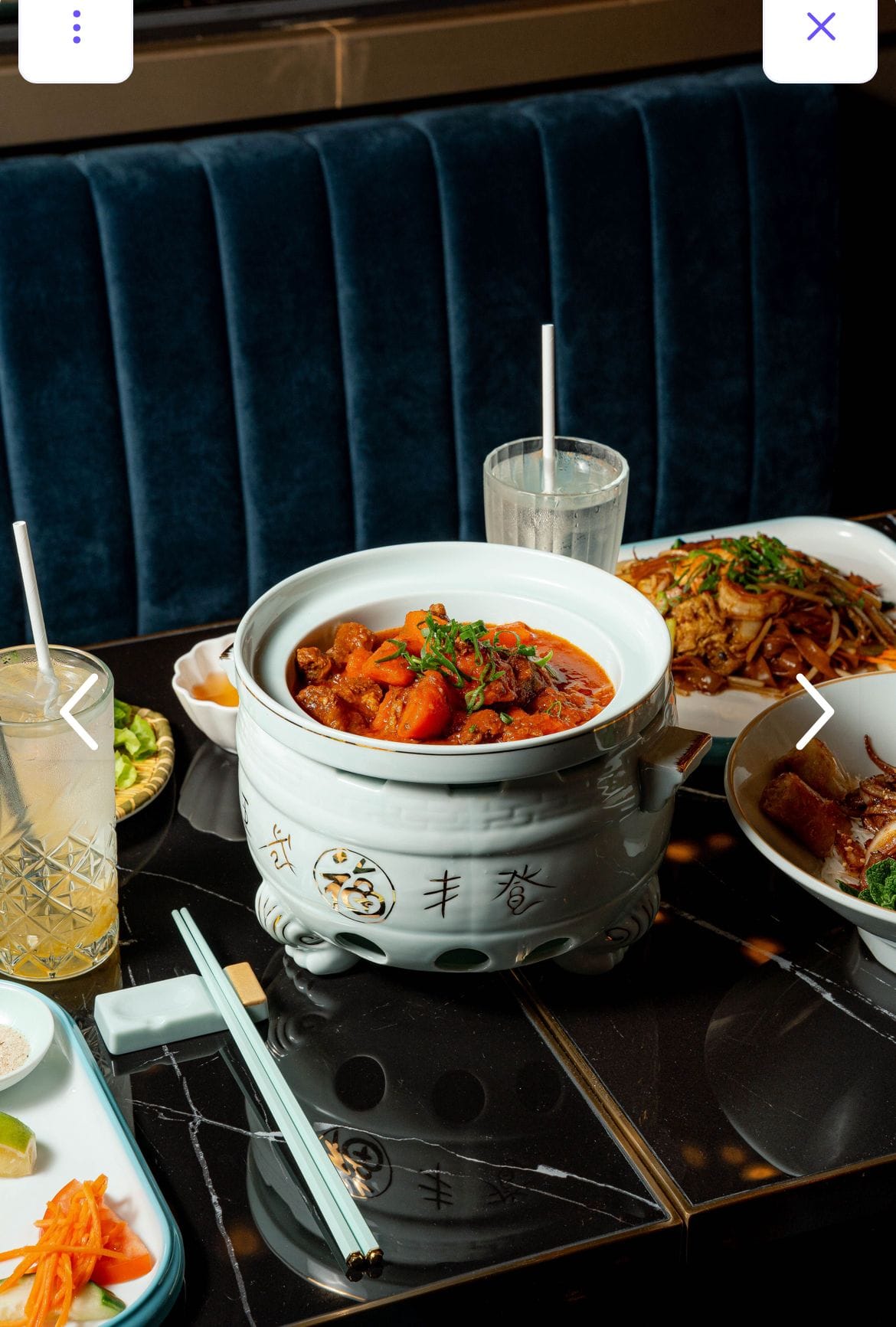 Marmite chinoise en céramique posée sur table marbre, banquette velours en arrière-plan