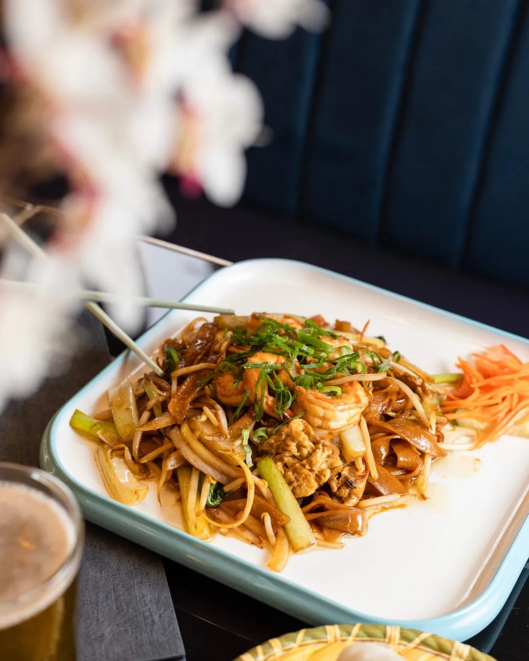 Stir-fried rice noodles with prawns plated on veined black marble