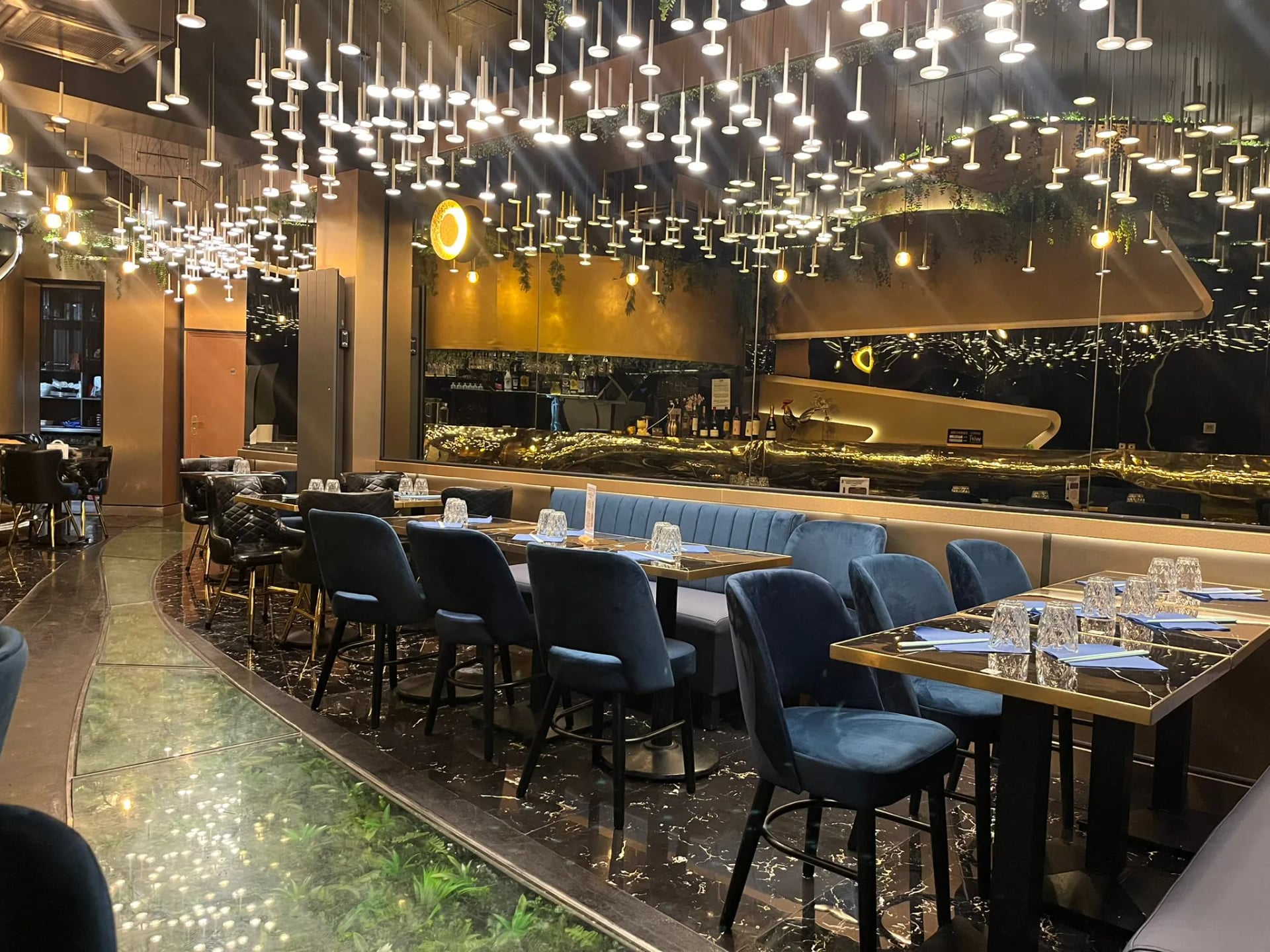 Night-blue velvet banquettes and crystal chandeliers cascade in the Phở 98 salon